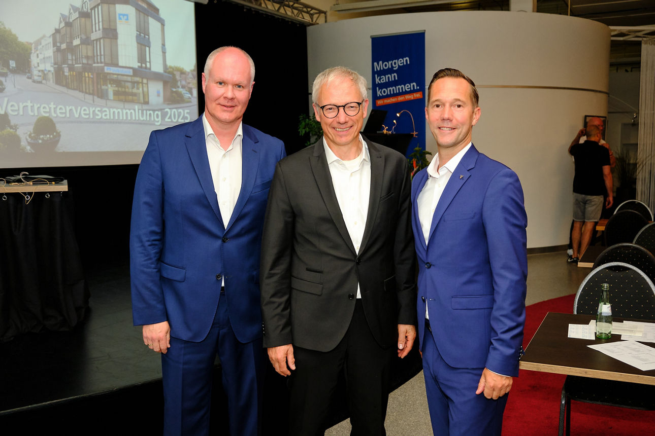 Der Aufsichtsratsvorsitzende Christian Alberts sowie die Bankvorstände Markus Knauf und Michel Rathmackers stehen nebeneinander im Anzug.