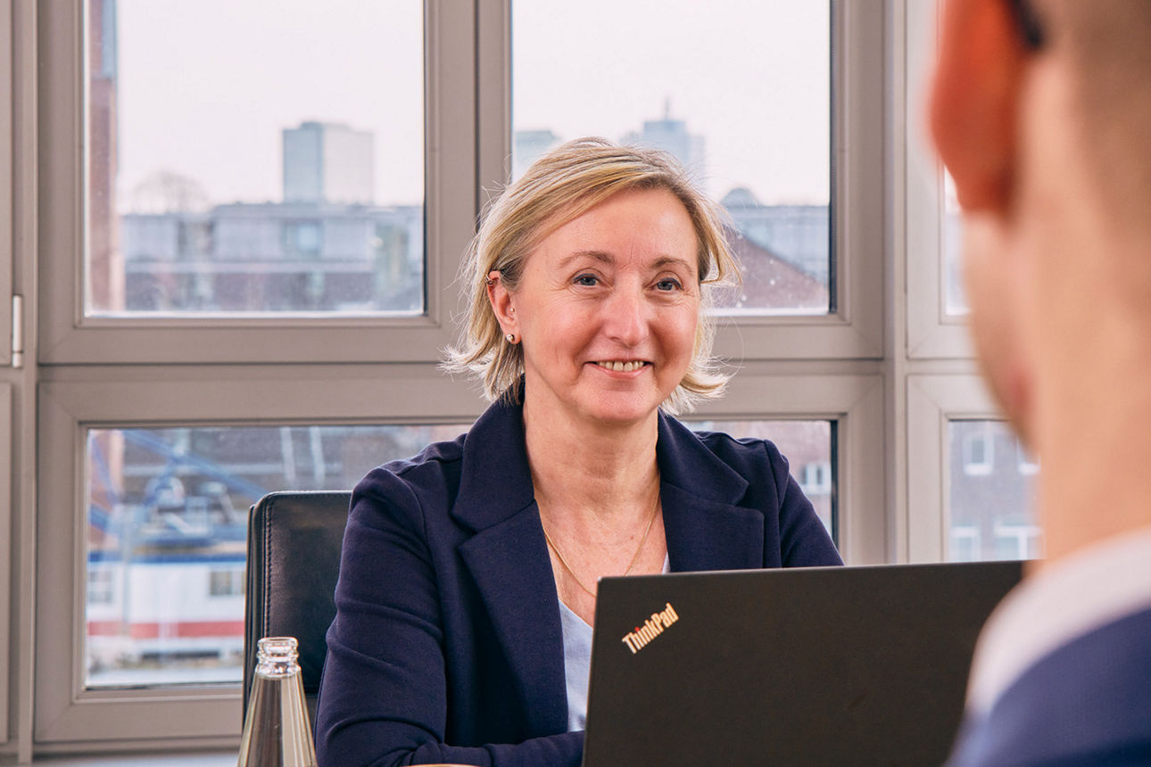 Eine Frau sitzt lächelnd in hellen Büroräumen