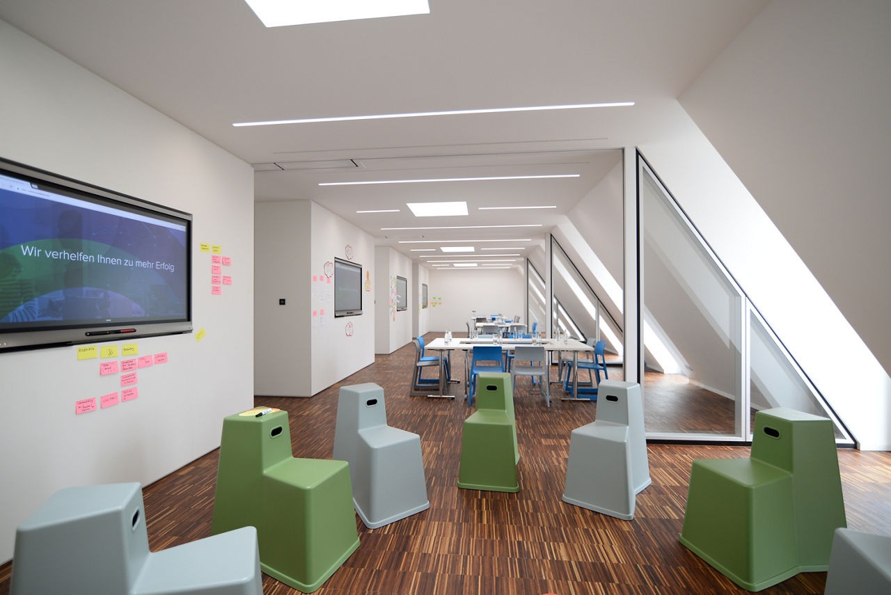 Schulungsraummit bunten Sitzhockern und Monitoren