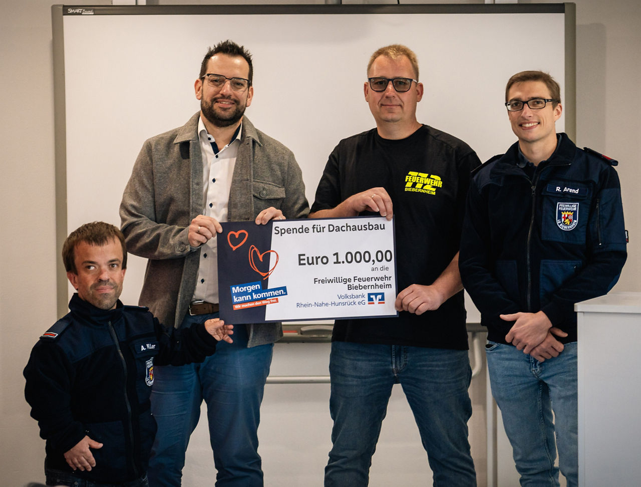 Vier Erwachsene halten einen Spendenscheck in der Hand.