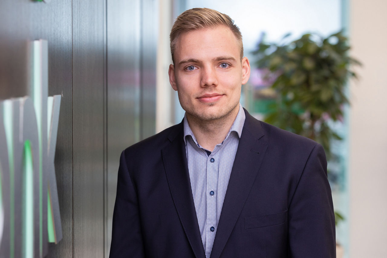 Ein Mann mit Anzug mit einem Büro im Hintergrund. 