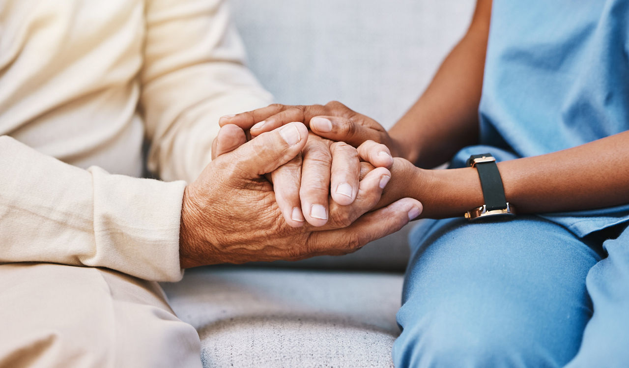 Krankenpflegerin hält die Hand eines Seniors zur Unterstützung