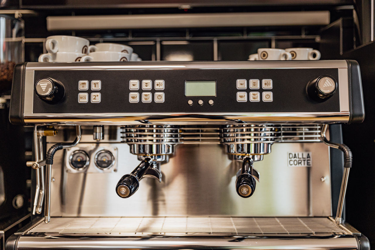 Frontansicht einer professionellen Siebträgermaschine mit zwei Brühgruppen, Bedienelementen und abgestellten Tassen.