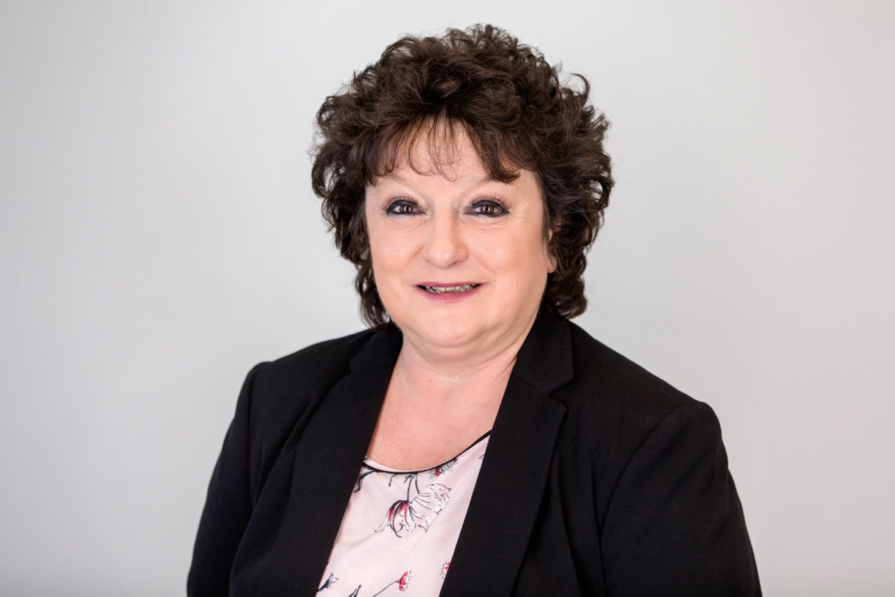 Eine lächelnder Frau schaut in die Kamera.