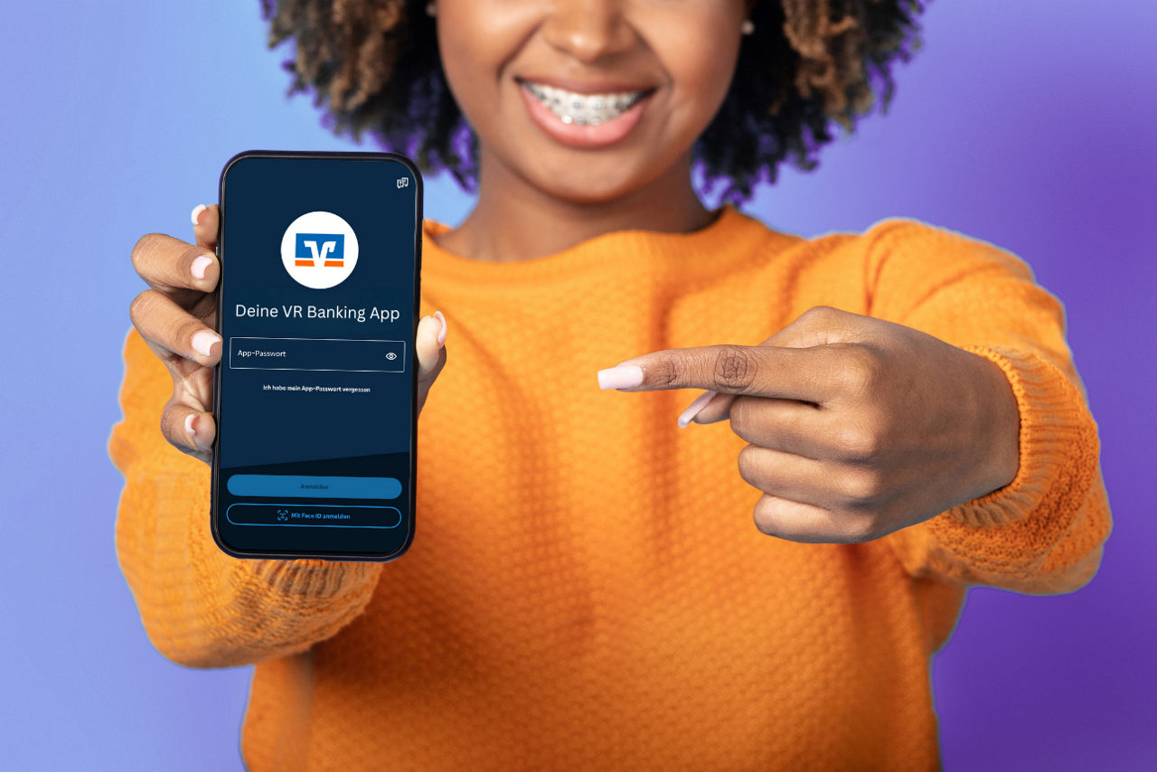 Frau zeigt auf ihr Handy mit der VR Banking App