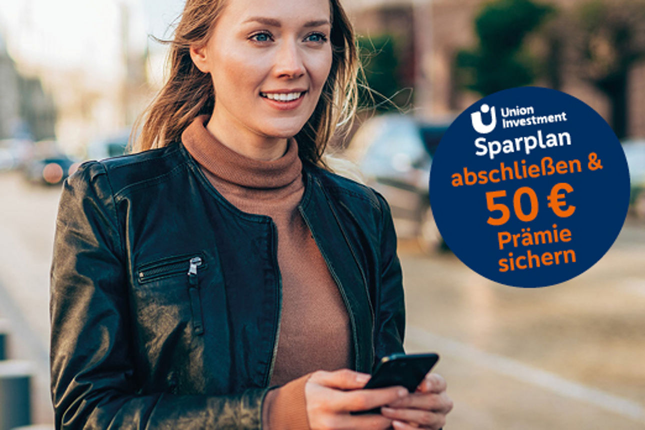 Junge Frau läuft mit dem Handy in der Hand an einer Straße entlang