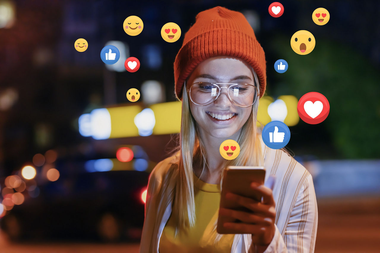 Mädchen hält Handy in der Hand und ums sie rum sind ganz viele Emojes