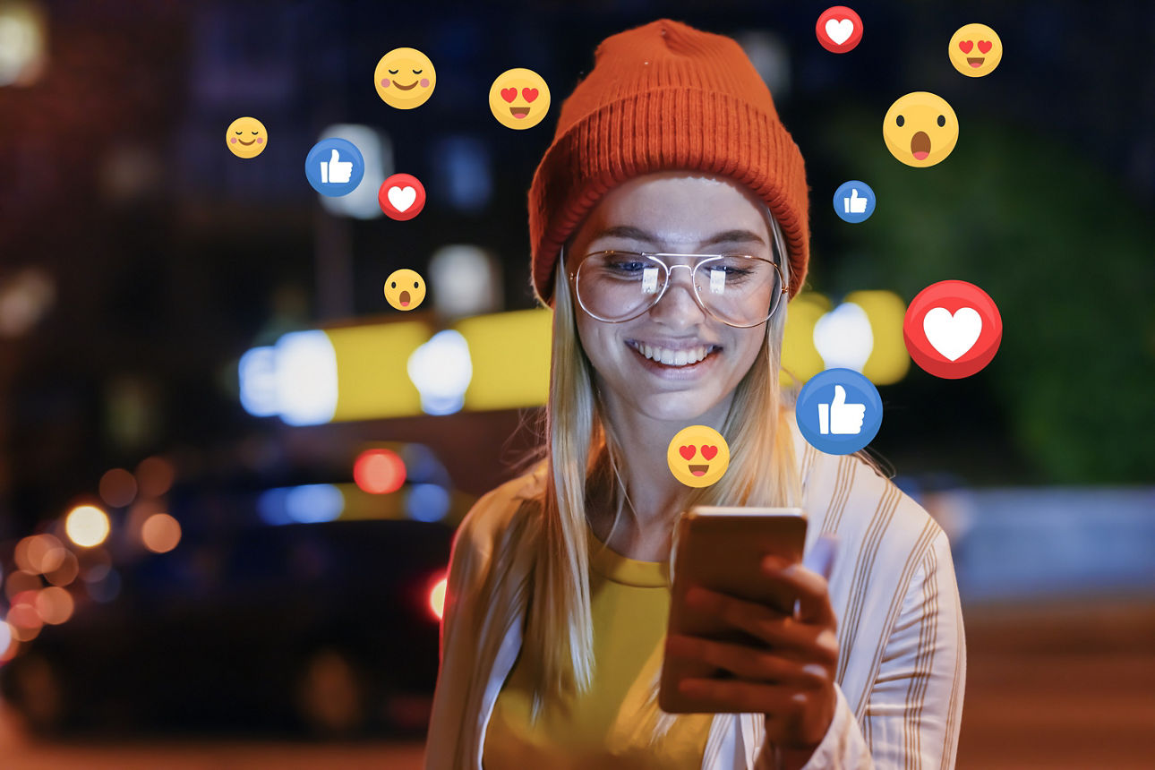 Mädchen hält Handy in der Hand und ums sie rum sind ganz viele Emojes