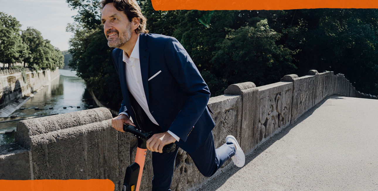 Mann im Anzug auf E-Scooter