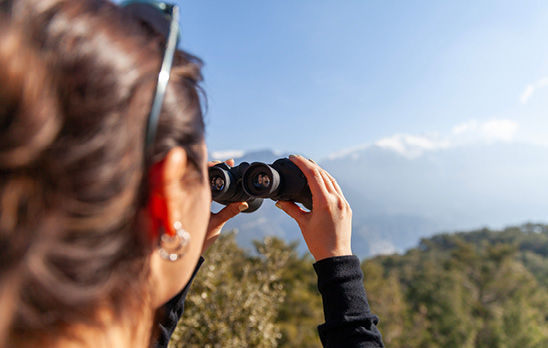 Eine Frau schaut durch ein Fernglas auf eine schöne Landschaft