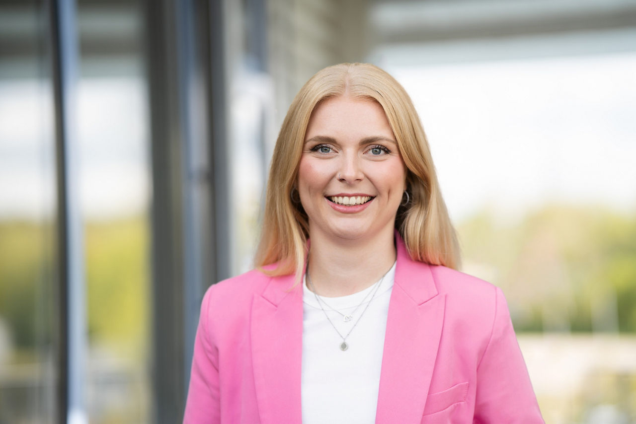 blonde Frau mit pinken Blazer lacht