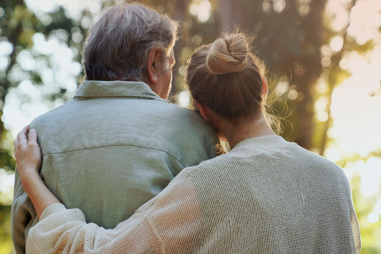 Eine Frau legt einem älteren Mann ihre Hand auf den Rücken