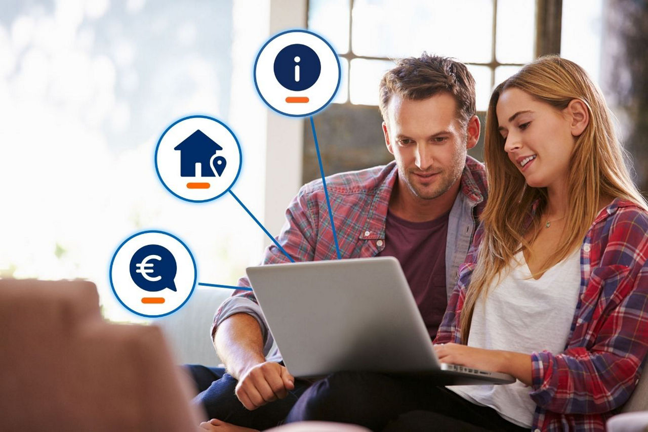 Ein junges Paar sitzt entspannt auf der Couch und blickt zusammen auf den Laptop