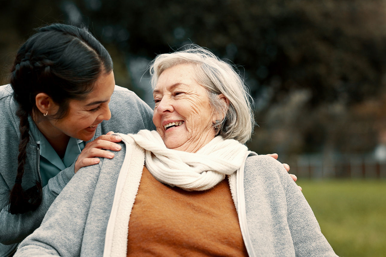 Eine Pflegerin umarmt ihre Patienten und sie lachen sich an
