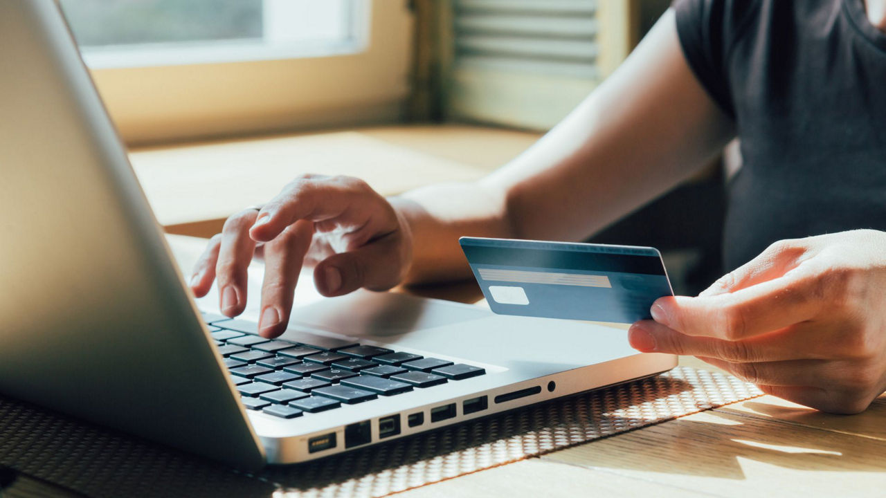 Eine Person sitzt am Laptop, hält seine girocard und tippt