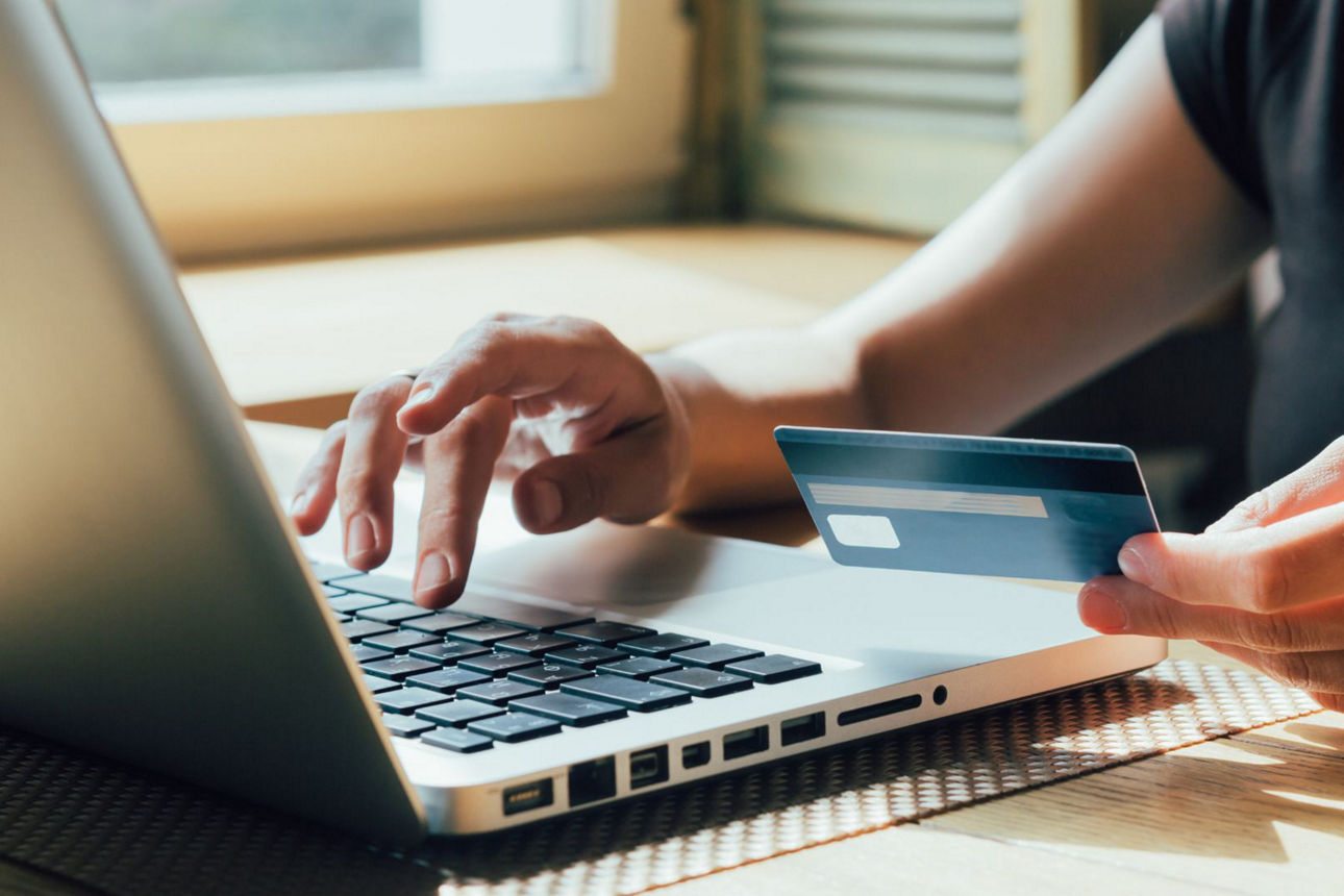 Eine Person sitzt am Laptop, hält seine girocard und tippt
