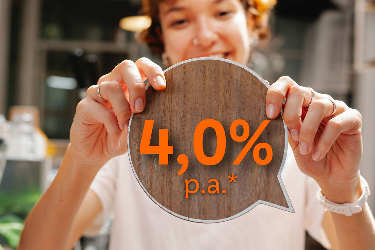Frau hält runde Holztafel mit 4,0% p. a. hoch