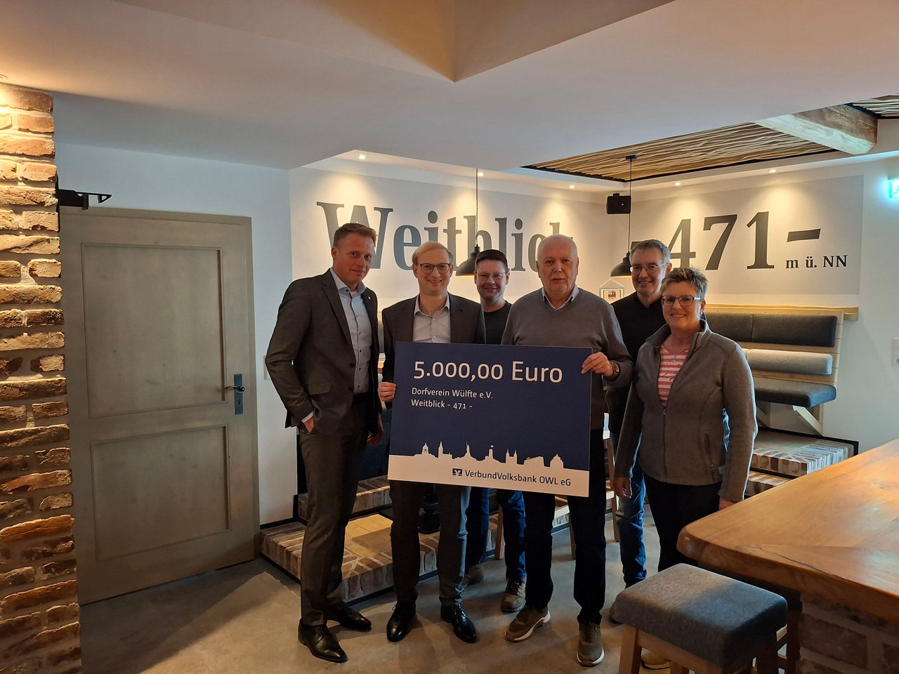 Vertreter der Volksbank Brilon und Vertreter der Dorfgemeinschaft Wülfte halten einen Spendenscheck über 5.000 Euro