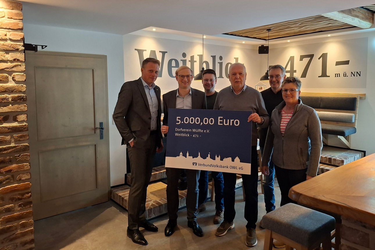 Vertreter der Volksbank Brilon und Vertreter der Dorfgemeinschaft Wülfte halten einen Spendenscheck über 5.000 Euro