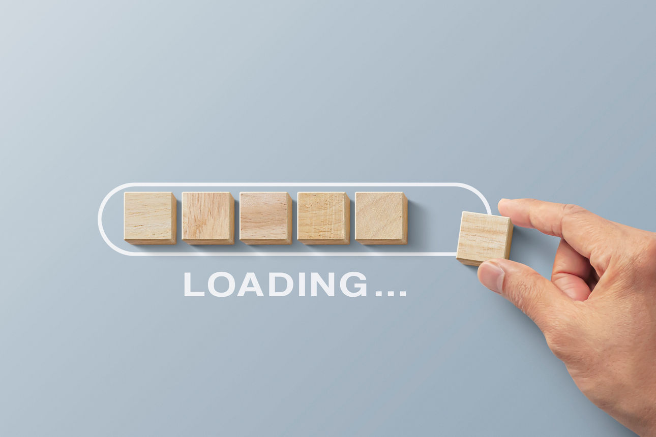 Loading, reboot, refresh or mindset concept. Hand putting wooden blocks in progress bar on gray background with the word LOADING.