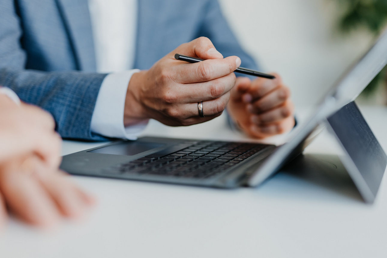 Hände von zwei Personen vor einem Laptop