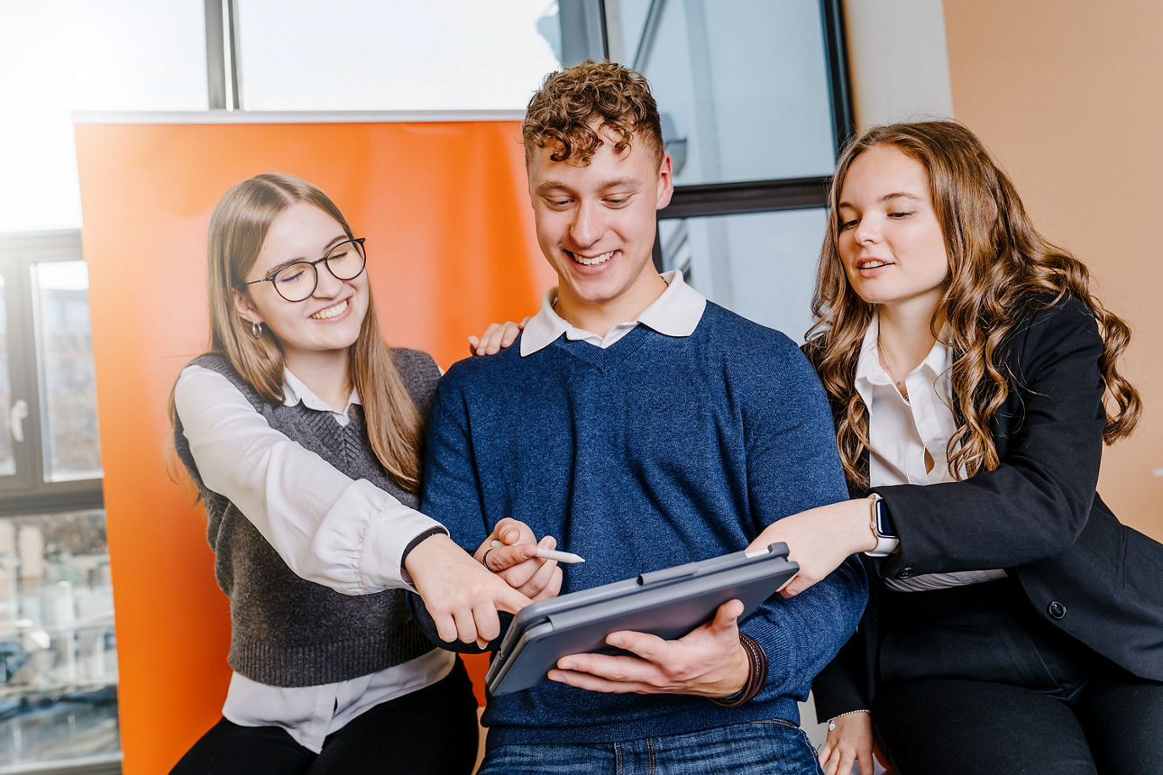 Drei Auszubildende deuten auf ein iPad