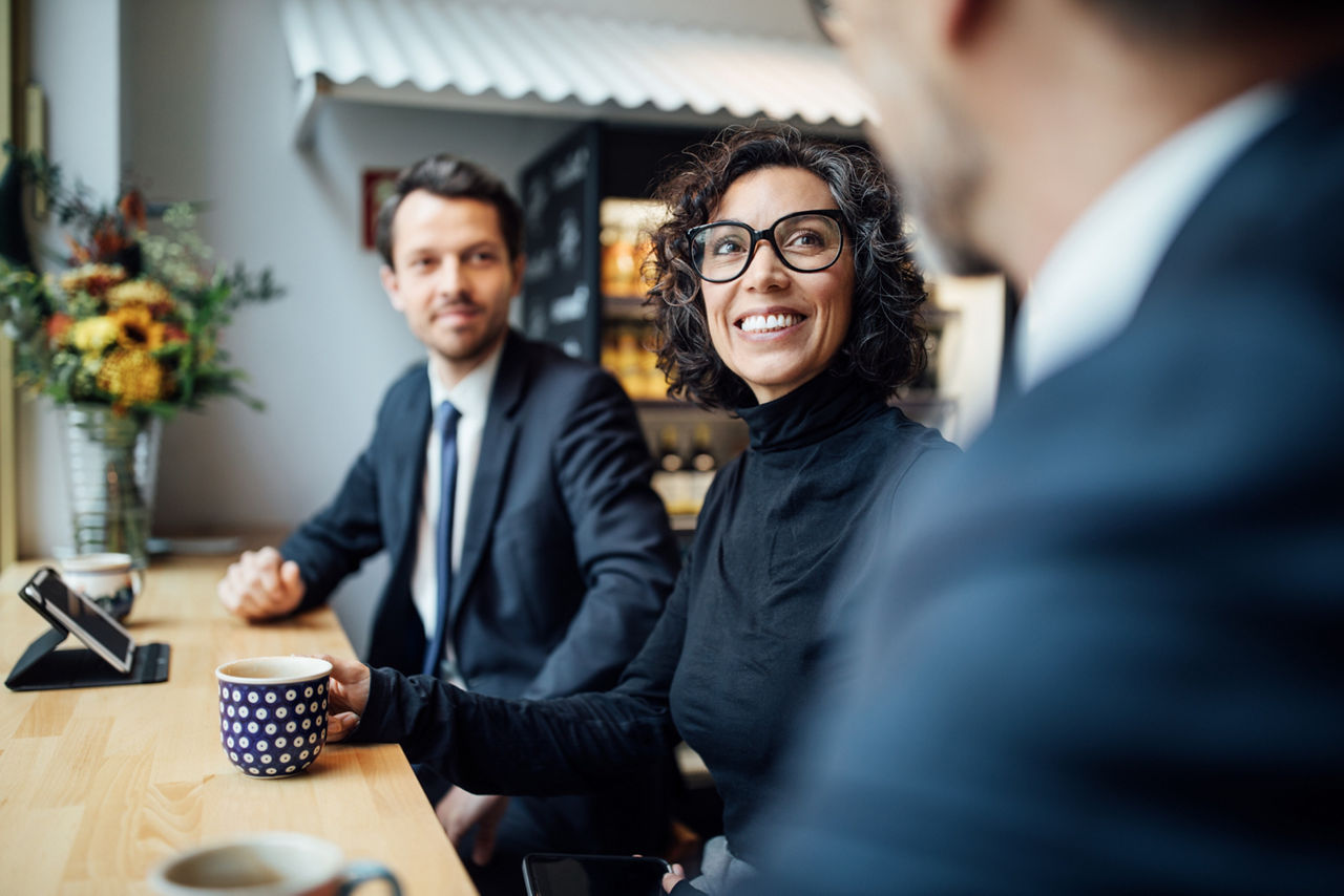 Drei Personen in Businesskleidung sitzen in einem Café