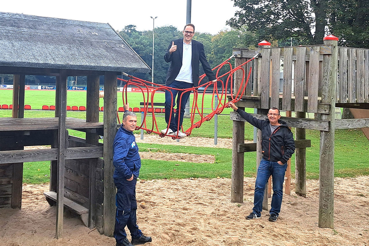 Drei-Männer-stehen-vor-einem-Klettergerüst