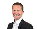 Ansprechpartner Patrick Drumm in einem Business Outfit lächelt in die Kamera