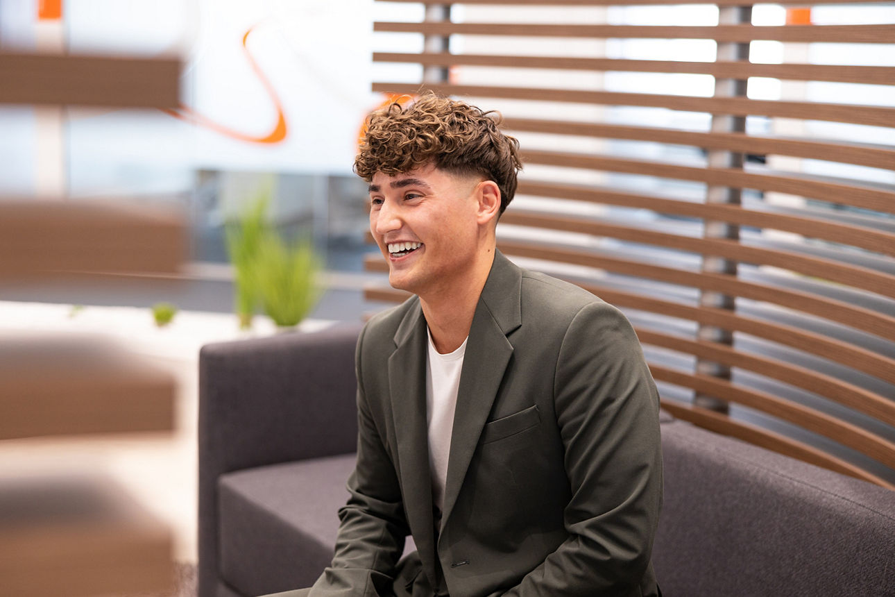 Lachender junger Mann in moderner Bankumgebung