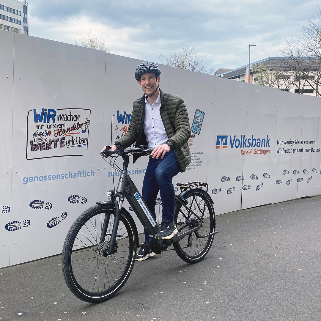 Jan Ackerhans auf dem E-Bike vor Volksbank Leistungen