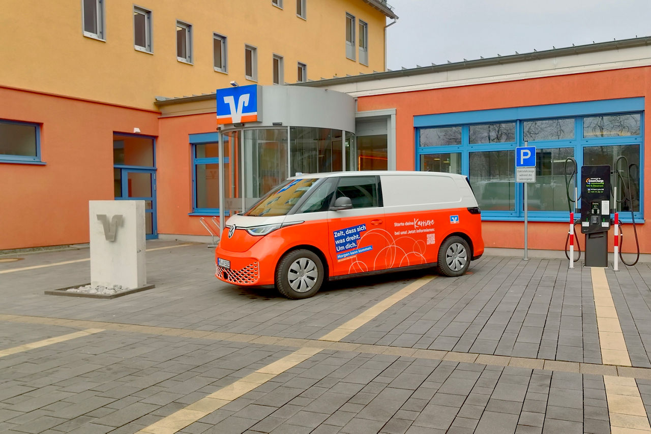 Auf einem Parkplatz steht ein orangener E Bus