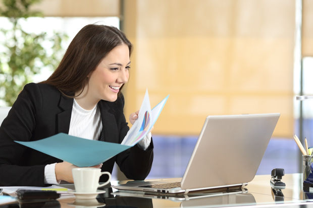 Happy executive comparing laptop content and documents