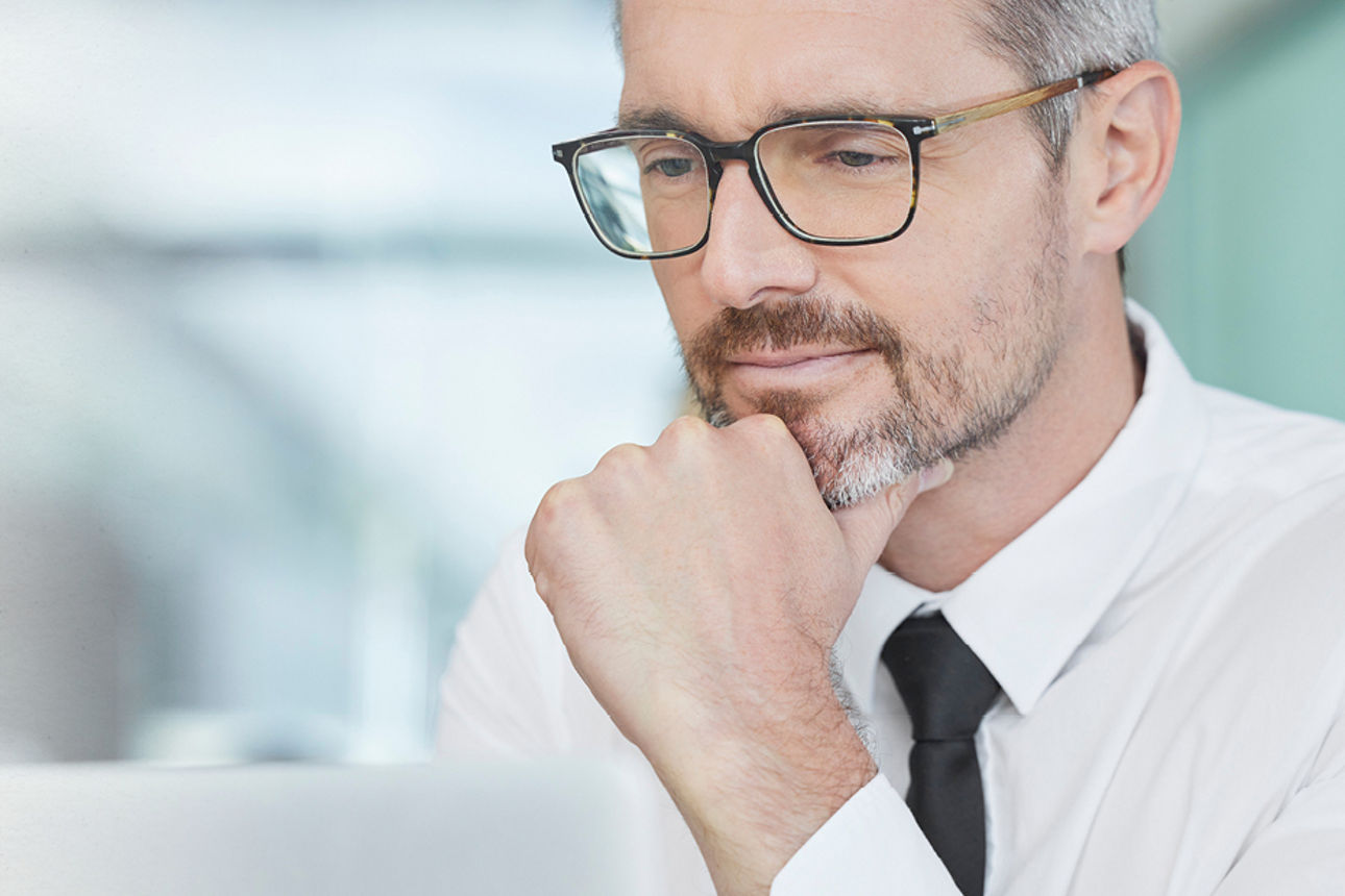 Öffentliche Fördermittel über die Hausbank erhalten - Man mit Brille guckt auf einen Bildschirm