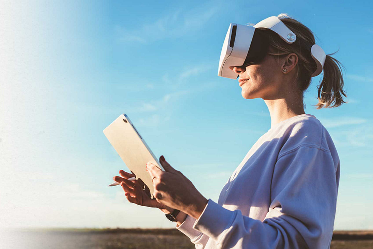 Weiterentwicklung der Leistungsvielfalt - Frau mit Tablet und VR-Brille guckt in die Weite