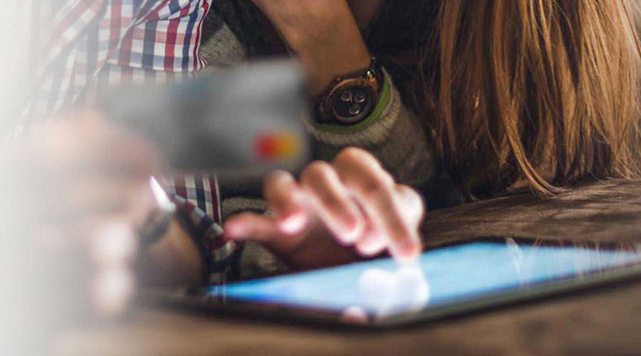 Visa Secure Päarchen tippt auf Laptop mit Kreditkarte in der Hand