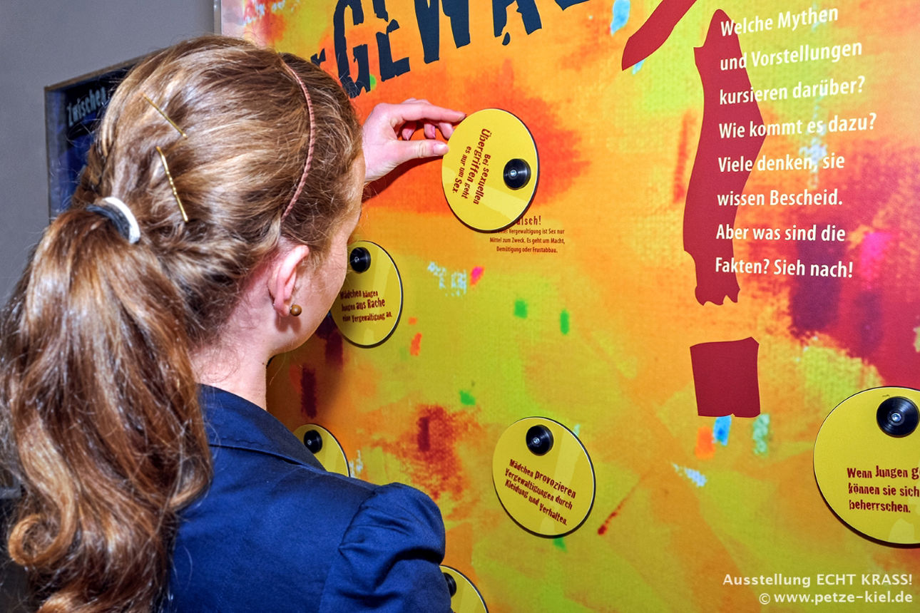 Person öffnet eine Klappe an einer interaktiven Ausstellungswand der Ausstellung „ECHT KRASS!“.