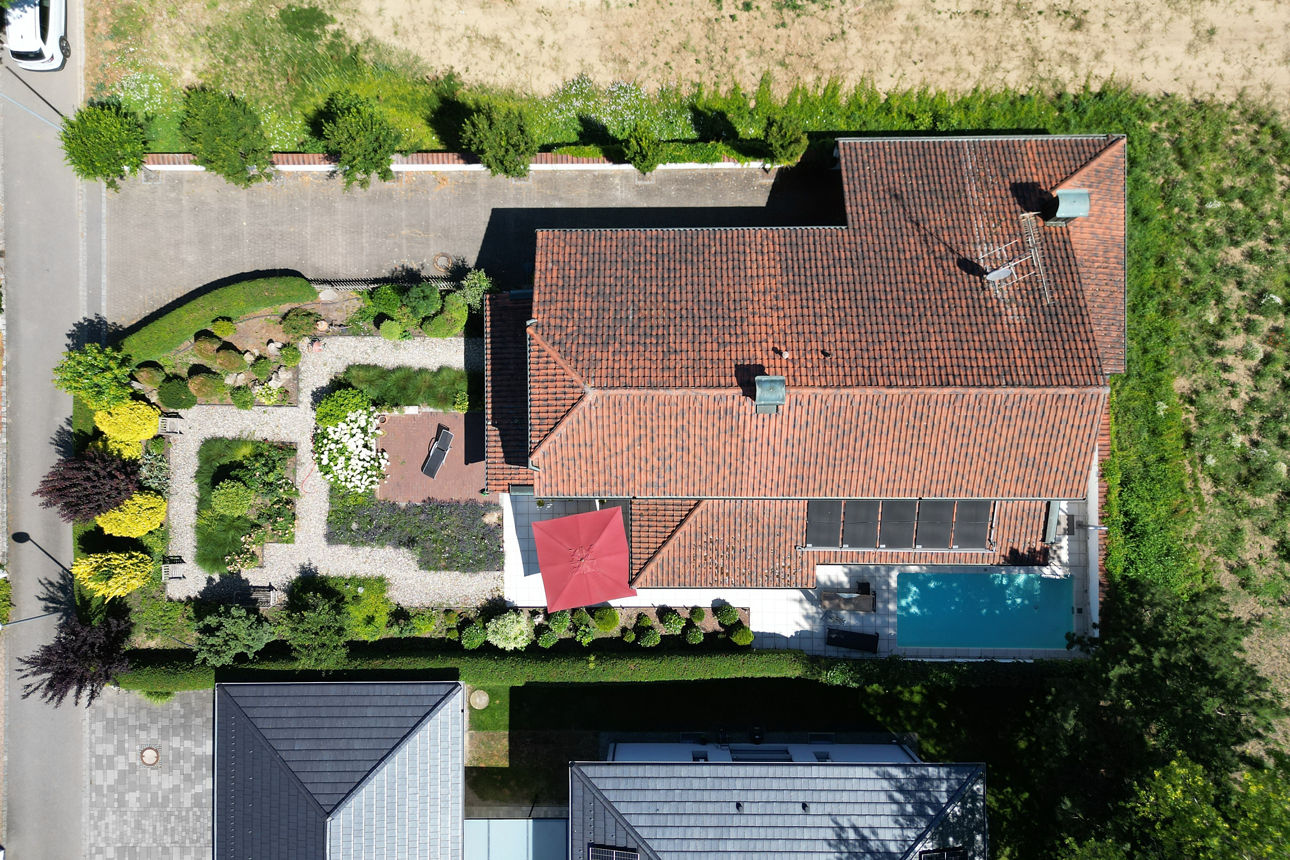 Auf dem Bild ist ein Grundstück von oben zu sehen, mit roten Dachziegeln und einem Pool