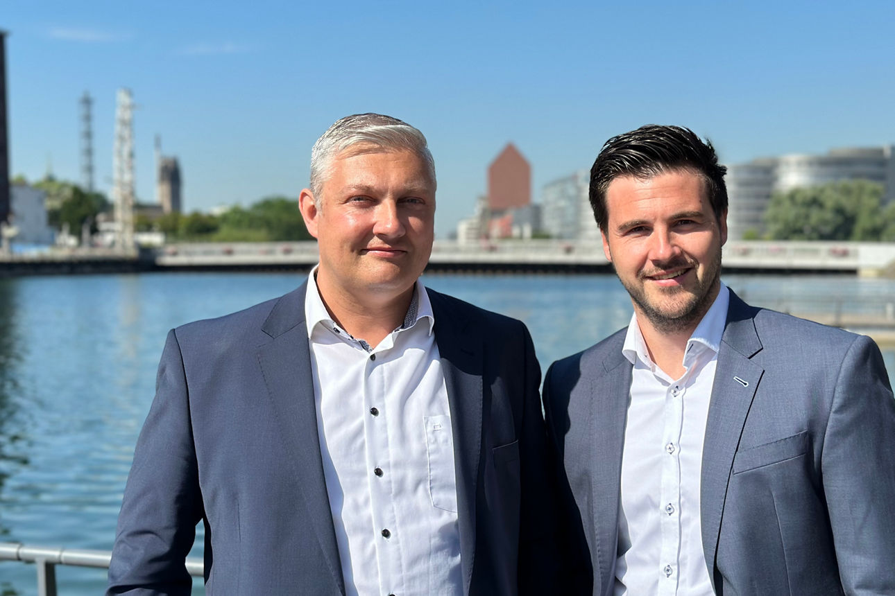 Zwei ESG-Berater stehen lächelnd im Duisburger Innenhafen zusammen