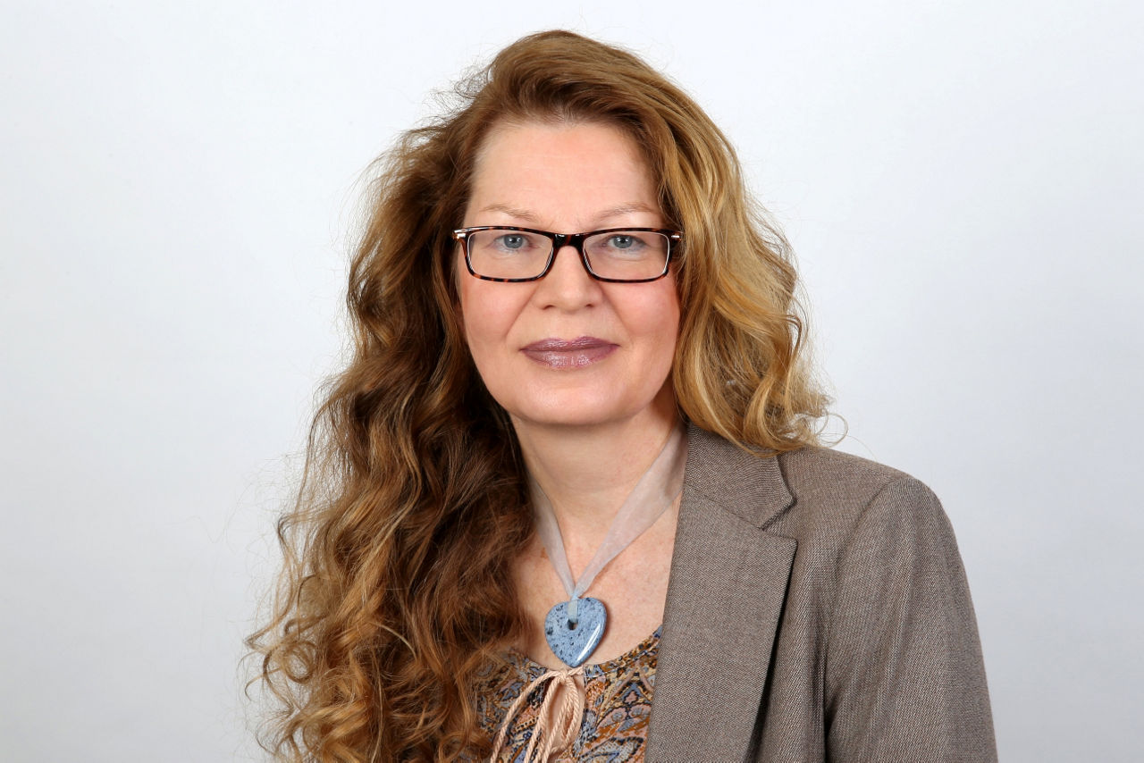 Eine lächelnder Frau schaut in die Kamera.