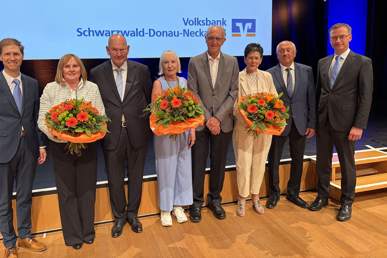 Eine Gruppe von Menschen, die bei einer Firmenveranstaltung der Volksbank Schwarzwald-Donau-Neckar auf einer Bühne stehen.