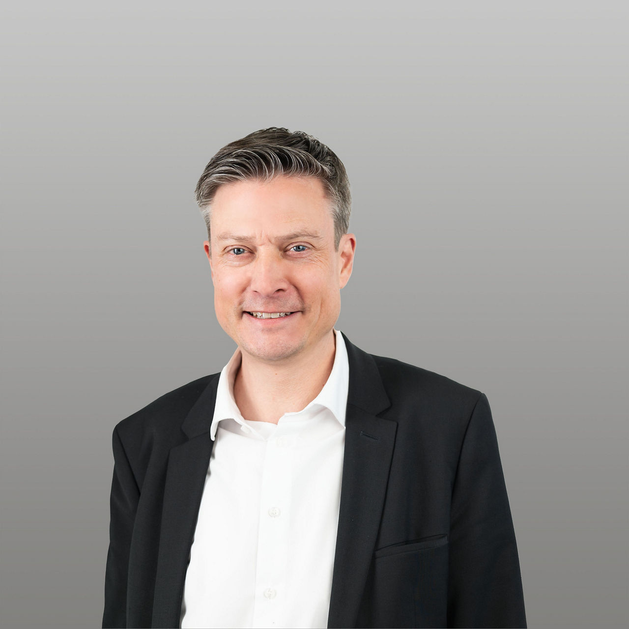 Firmenkundenbetreuer René Eickers vor grauem Hintergrund