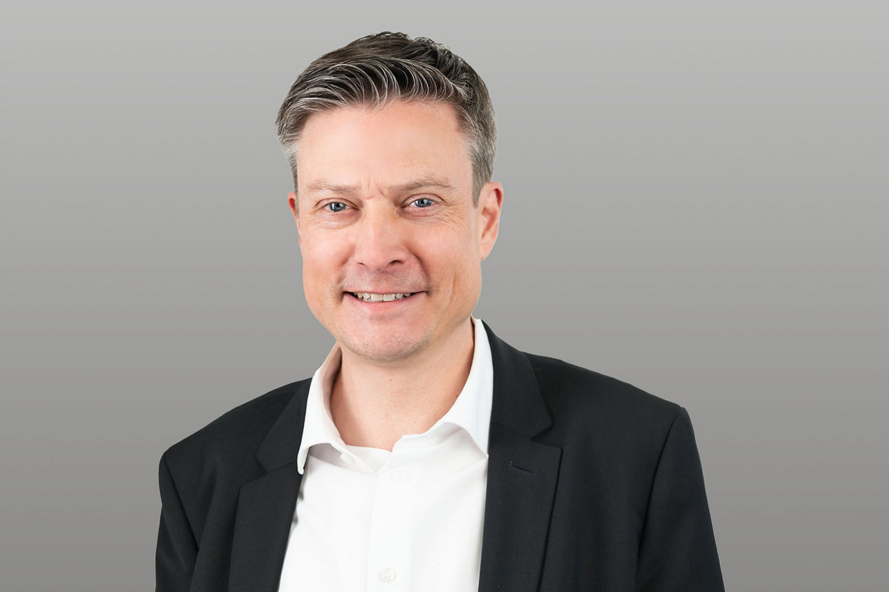 Firmenkundenbetreuer René Eickers vor grauem Hintergrund