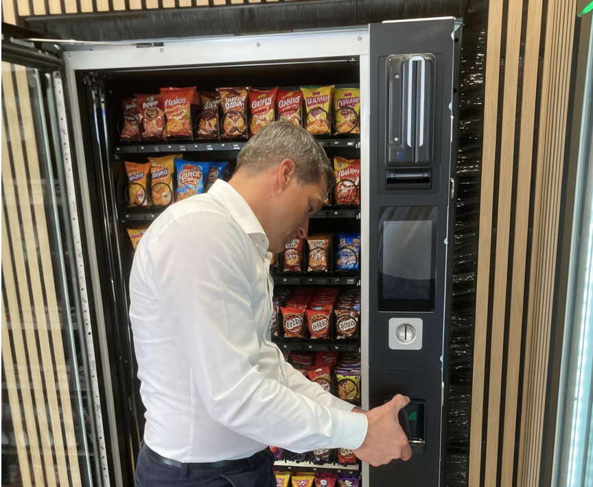 Mann baut ein Automatenterminal in einen Verkaufsautomaten ein.