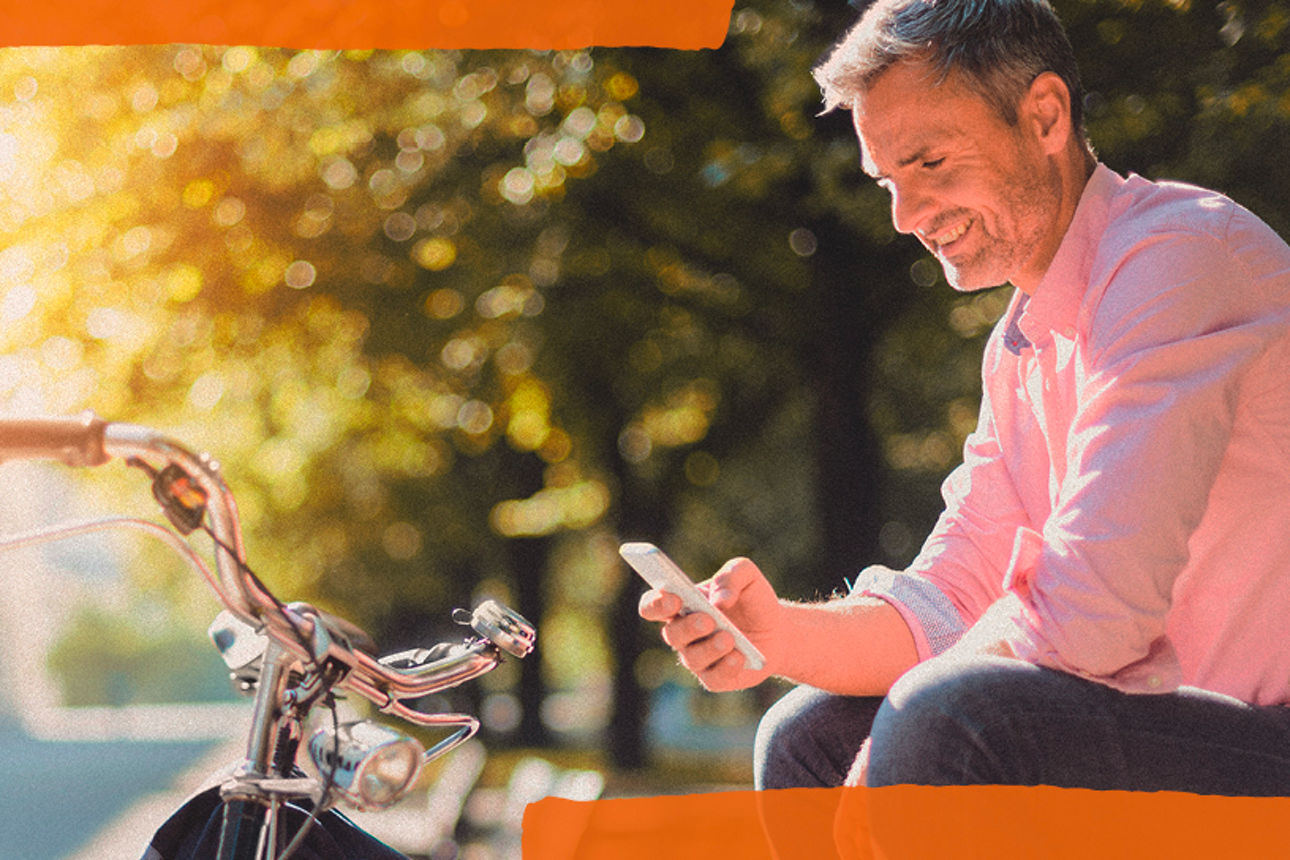 Ein Mann sitzt auf einer Bank und schaut in sein Handy