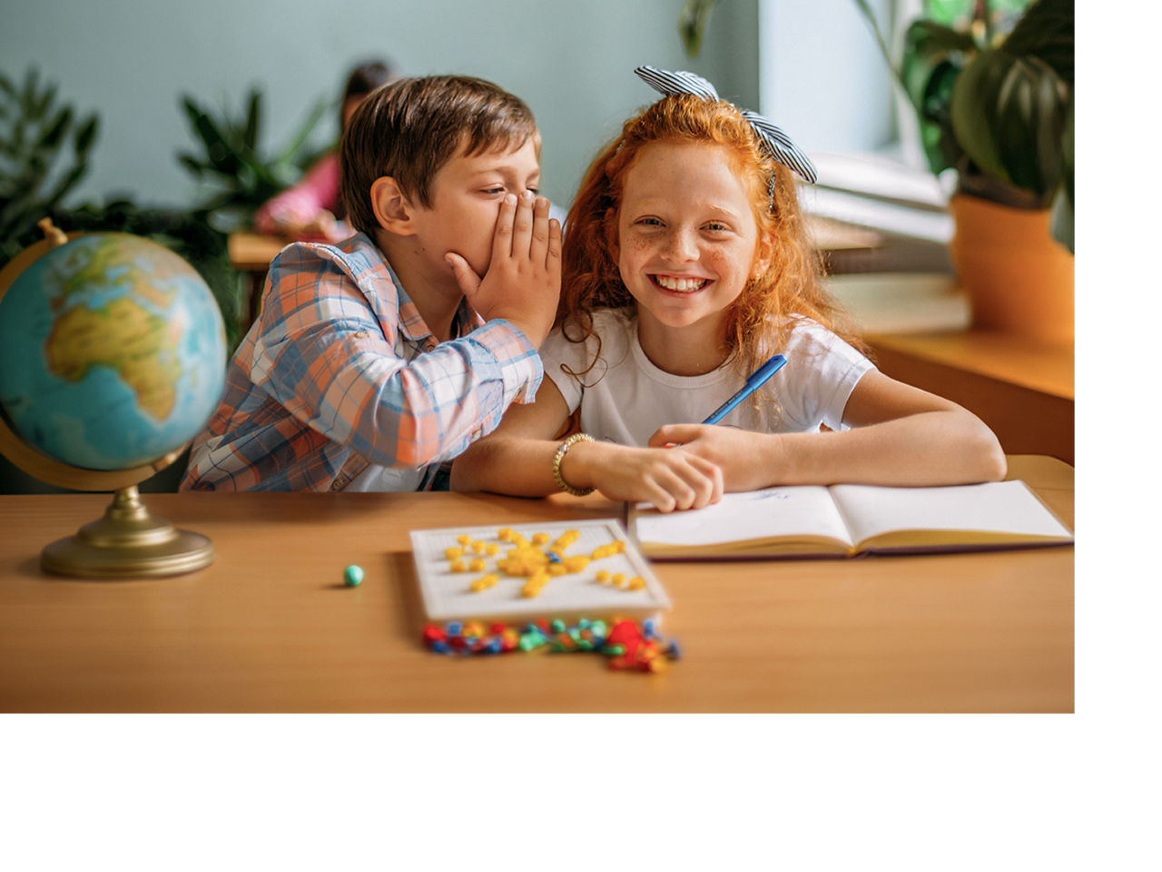 Junge und Mädchen mit Globus in der Schulbank