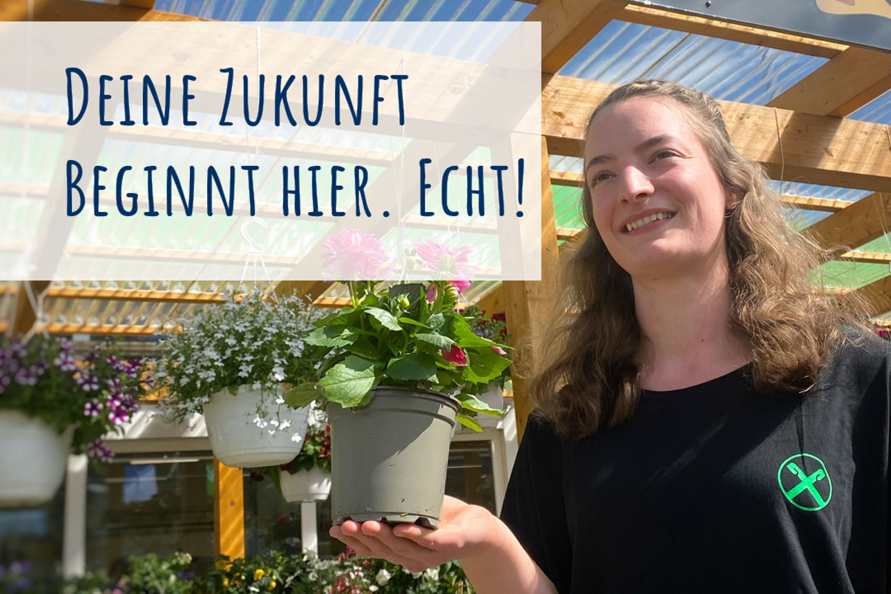 Der Azubi steht mit einem Blumentopf auf der Handfläche vor einem Geschäft, welches Blumen verkauft