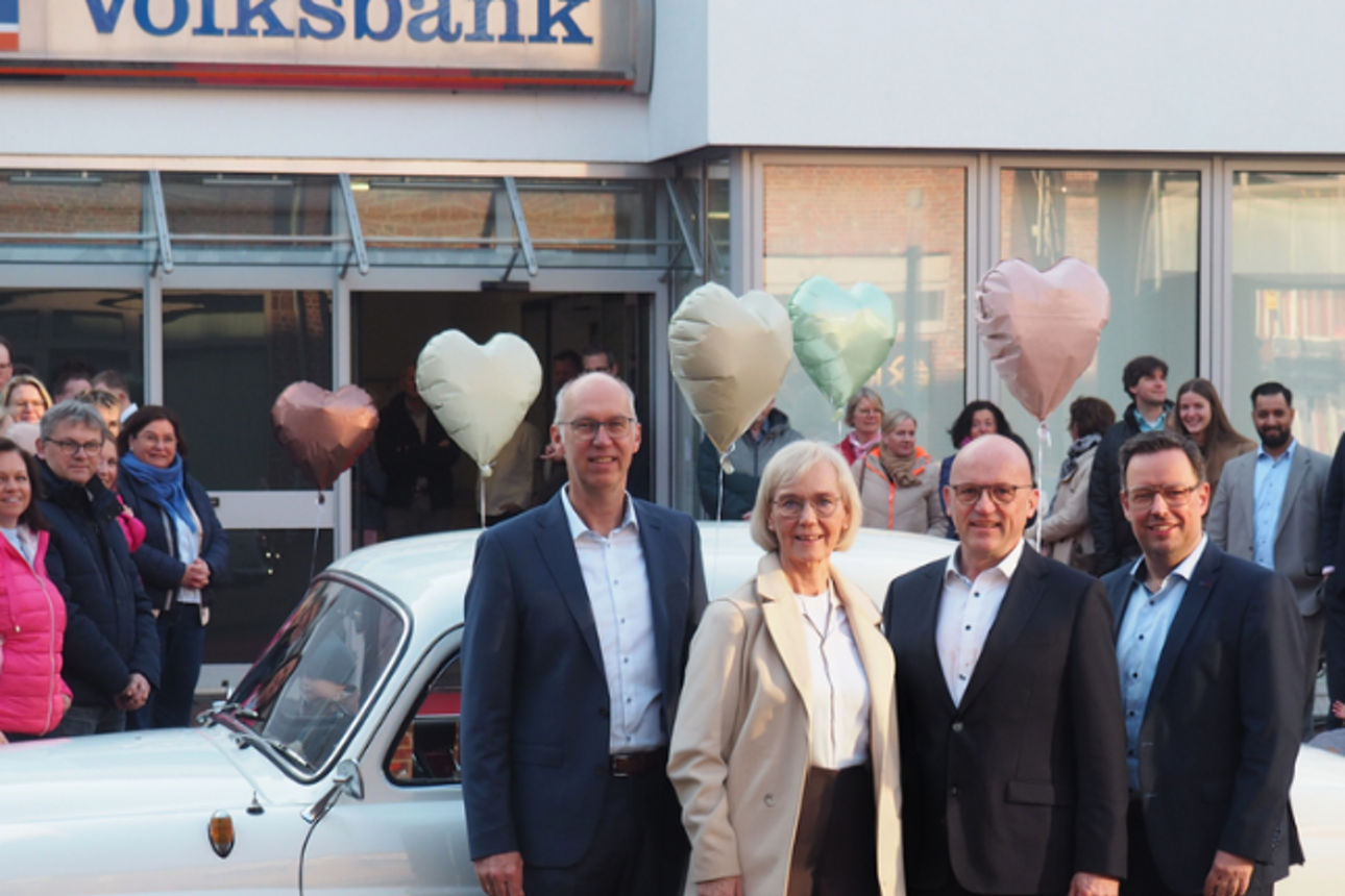 Der Vorstand und eine Kollegin stehen vor einem Auto. 