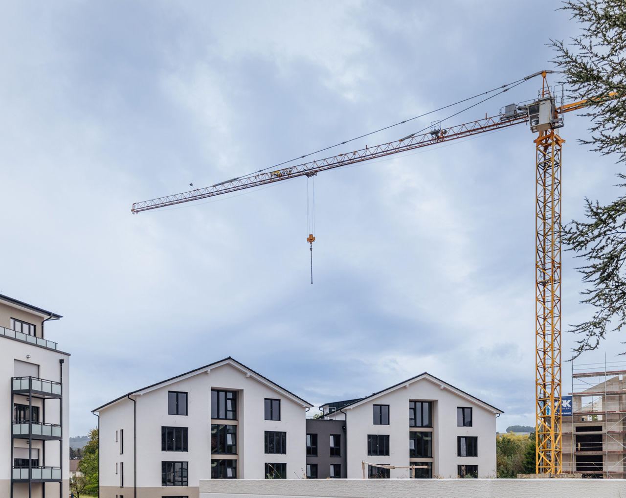 Ein Baukran ragt über mehrere Wohngebäude des Projekts ELMLAND1. Die Aufnahme zeigt den Baufortschritt mit fertiggestellten und im Ausbau befindlichen Gebäuden und dokumentiert die laufende Entwicklung des Wohnprojekts.