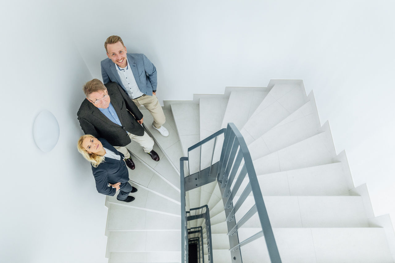 Blick von oben in ein hell gestaltetes Treppenhaus des Wohnprojekts ELMLAND1 mit gewendelten Stufen, klarem Geländer und moderner Innenraumgestaltung. Die Aufnahme zeigt einen funktionalen Gemeinschaftsbereich innerhalb des Wohnensembles.